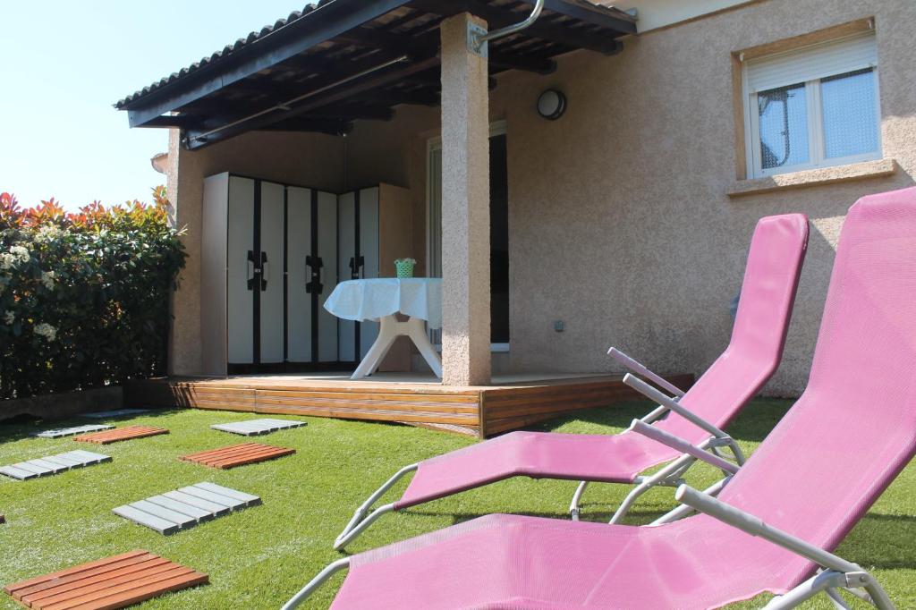 une paire de chaises roses dans la cour d'une maison dans l'établissement Graziosa villetta in residence con piscina a 100 m dalla spiaggia, à Cervione