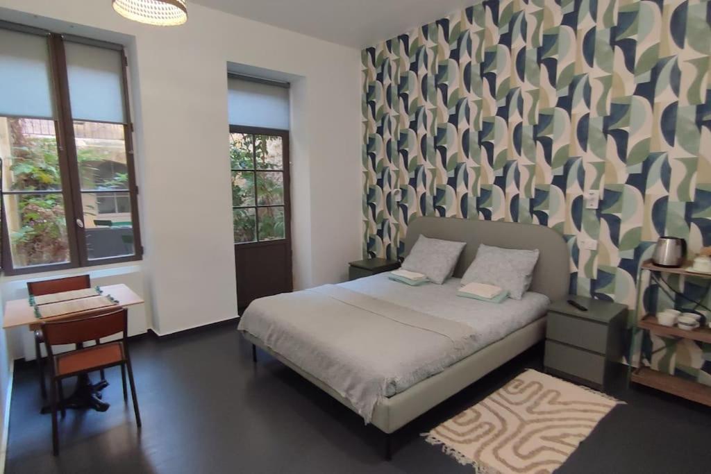 a bedroom with a bed and a desk and windows at Studio au cœur des Chartrons in Bordeaux
