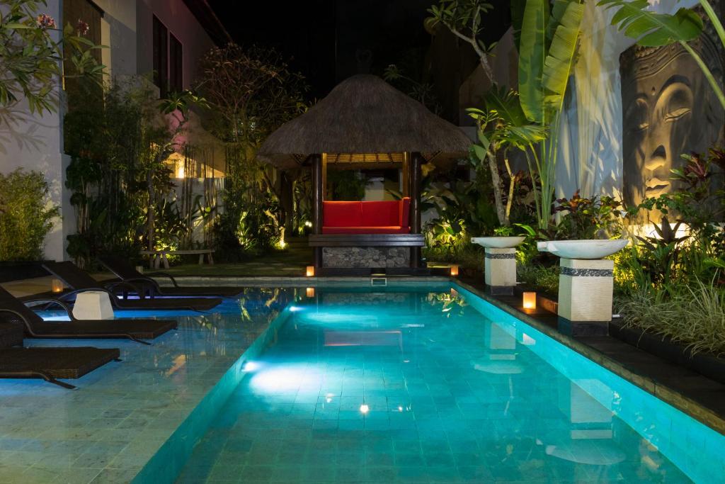 a pool in the middle of a resort at night at The Secret Villas in Seminyak