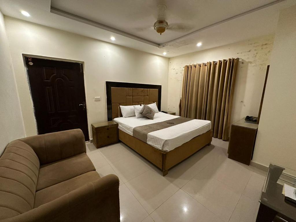 ein Schlafzimmer mit einem Bett, einem Stuhl und einem Sofa in der Unterkunft Hotel Green Fort Gulberg in Lahore