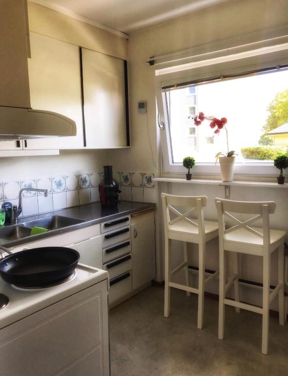eine Küche mit 2 Stühlen, einem Waschbecken und einem Fenster in der Unterkunft Fagersta Apatrtment in Fagersta