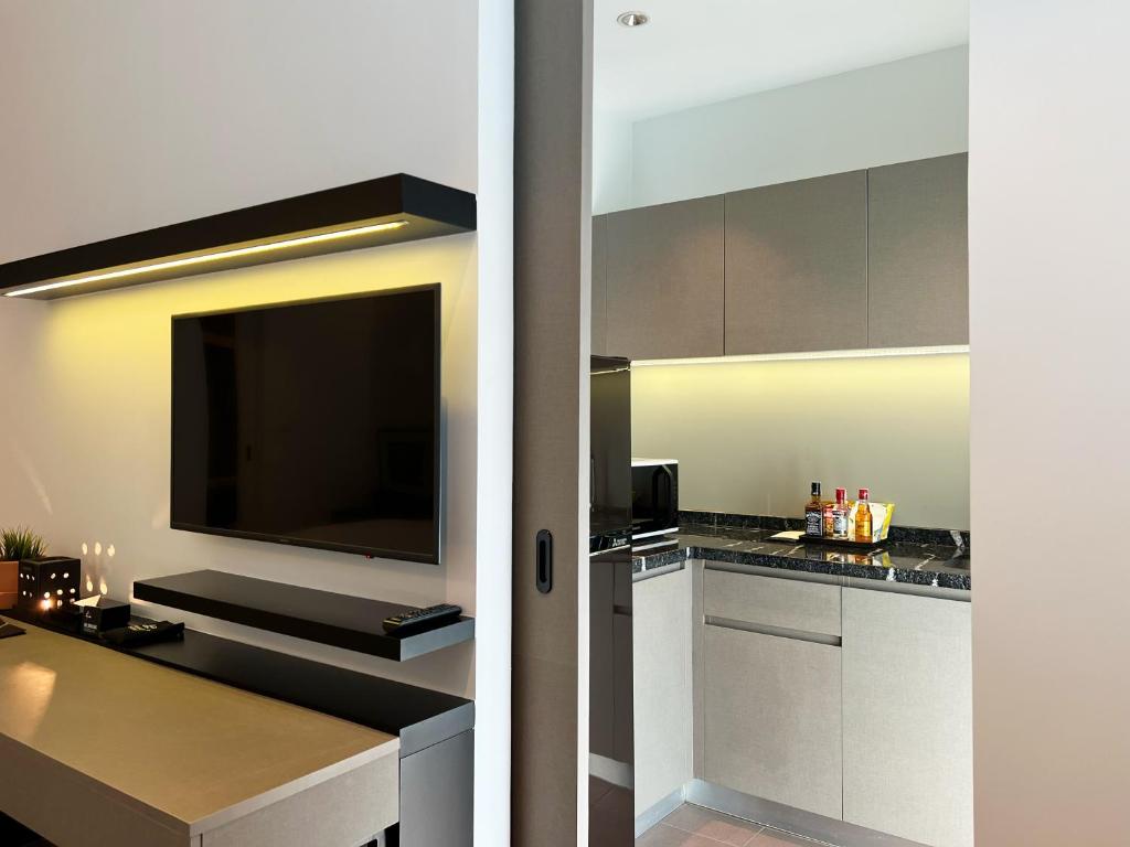 A built-in media wall faces a compact desk beside the room’s kitchenette.