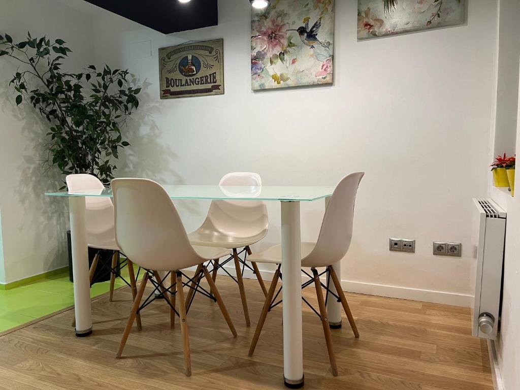 una mesa de cristal y sillas blancas en una habitación en Apartamentos El Olivo, en Valencia