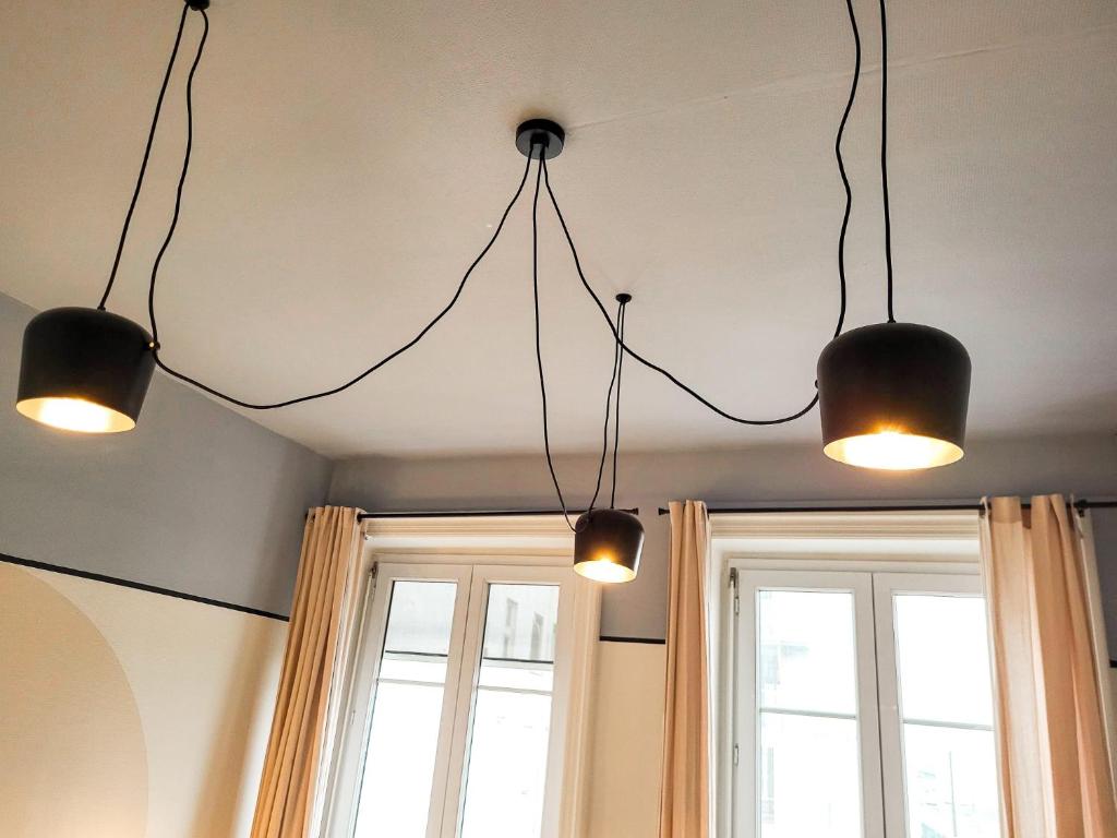 three lights hanging from a ceiling with two windows at Suite Oxymore in Lyon