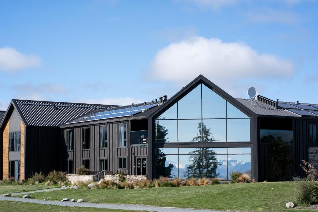 ein großes schwarzes Gebäude mit Glasfenstern in der Unterkunft Haka House Lake Tekapo in Lake Tekapo