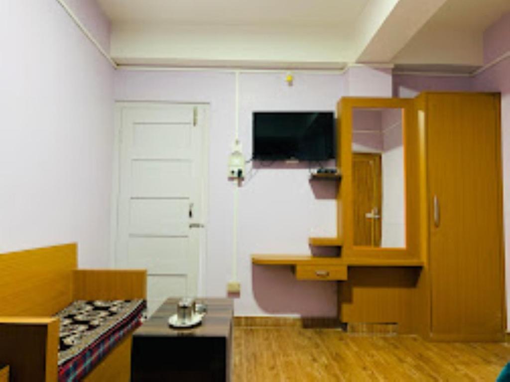 Bomdila的住宿－Hotel Cozi Inn Bomdila，客房设有带桌子和电视的厨房。