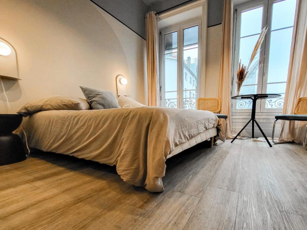 a bedroom with a large bed in a room with windows at Suite Oxymore in Lyon