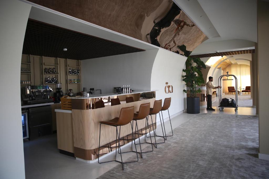 a bar with stools in a room with a person standing in the background at أجنحة درة Dorra Suites in Riyadh