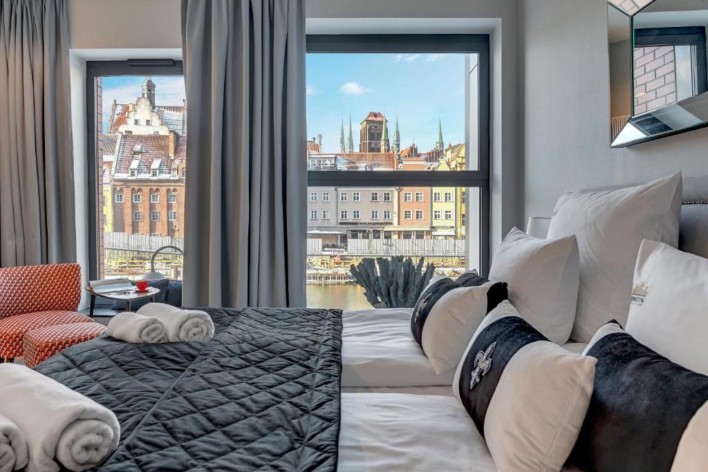 um quarto com uma cama e uma grande janela em Deo Plaza Riverside & Radisson SPA by Downtown Apartments em Gdansk