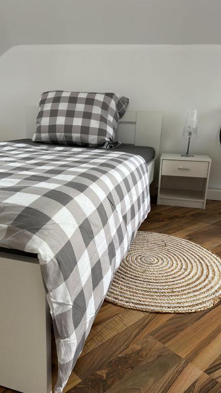 a bed with a black and white checkered pillow and a rug at Schönes Zimmer im Zentrum - 3 in Paderborn
