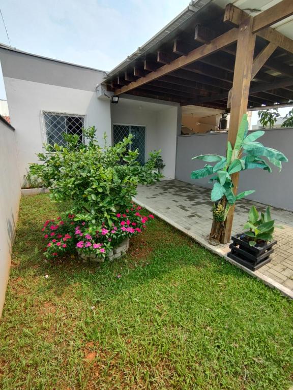dom z ogrodem z kwiatami na dziedzińcu w obiekcie Casa de Praia Balneário Piçarras w mieście Balneário Piçarras