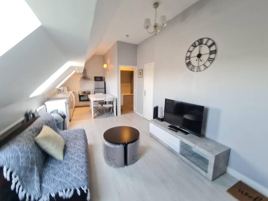 un salon avec un canapé et une horloge au mur dans l'établissement Modern Family House near Astérix Airport Chantilly, à Orry-la-Ville