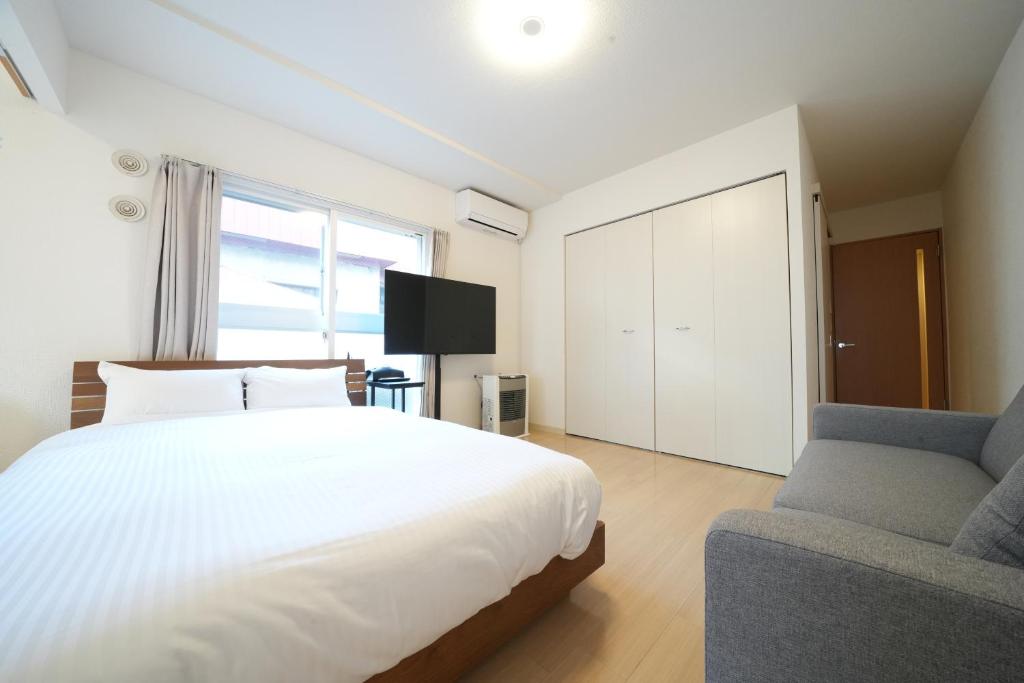 Residence Hotel Liberte في سابورو: غرفة نوم بسرير ابيض وكرسي