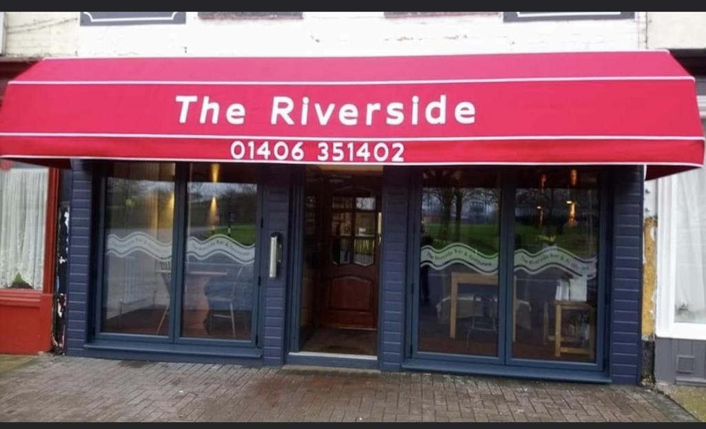 a red awning over the entrance to a restaurant at The Riverside in Sutton Bridge