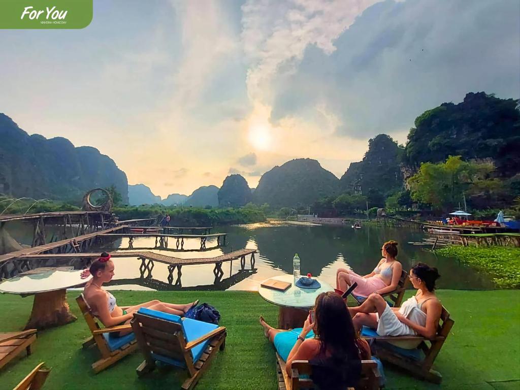 a group of people sitting on chairs by a river at For You Homestay in Ninh Binh