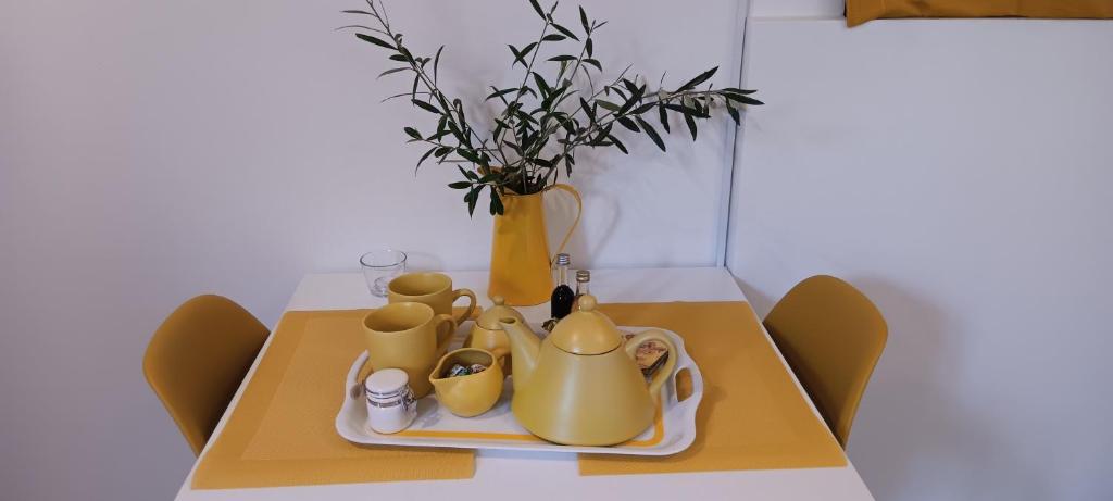 Athenian Asty Guesthouse في أثينا: طاولة مع مجموعة شاي صفراء و مزهرية