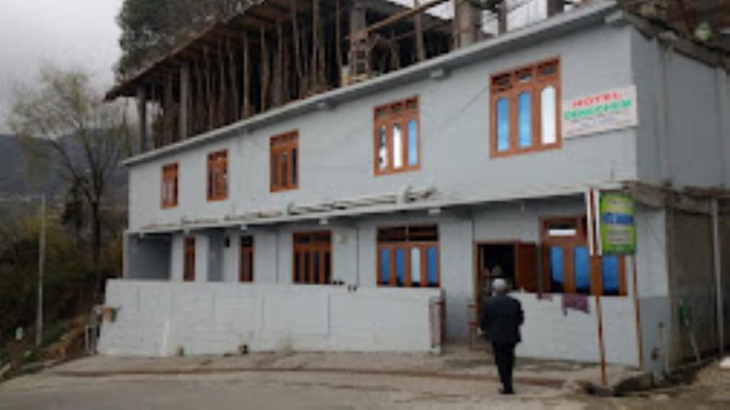 a man walking past a building under construction at HOTEL DENGCHEM Bomdila in Bomdila