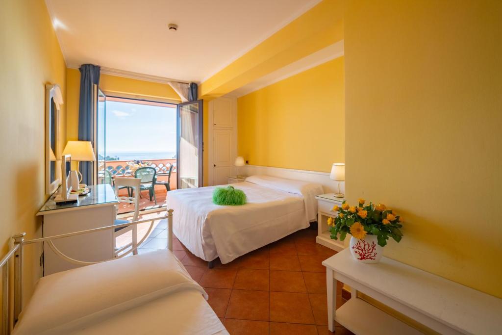 a hotel room with two beds and a balcony at Mendolia Beach Hotel in Taormina