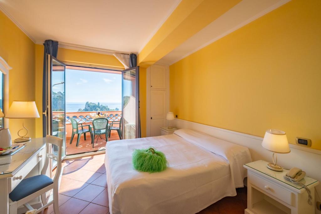 a hotel room with a bed and a balcony at Mendolia Beach Hotel in Taormina