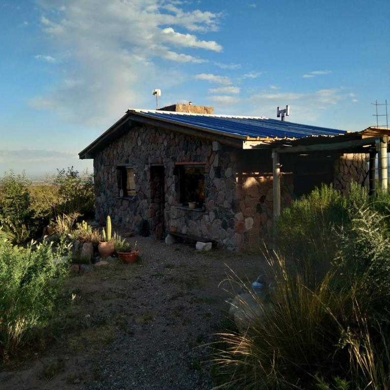 una pequeña casa de piedra con techo azul en Refugio de Montaña "Casa Chakana " en Luján de Cuyo