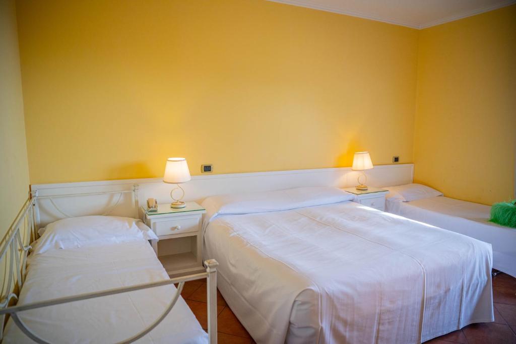 two beds in a room with yellow walls at Mendolia Beach Hotel in Taormina