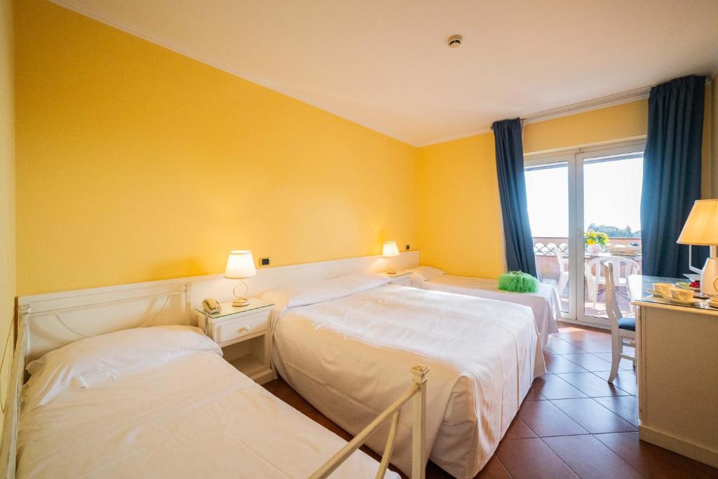 a hotel room with two beds and a window at Mendolia Beach Hotel in Taormina