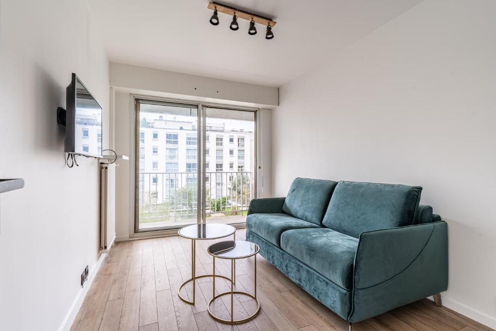 un salon avec un canapé vert et une fenêtre dans l'établissement Magnifique Studio neuf, à Paris
