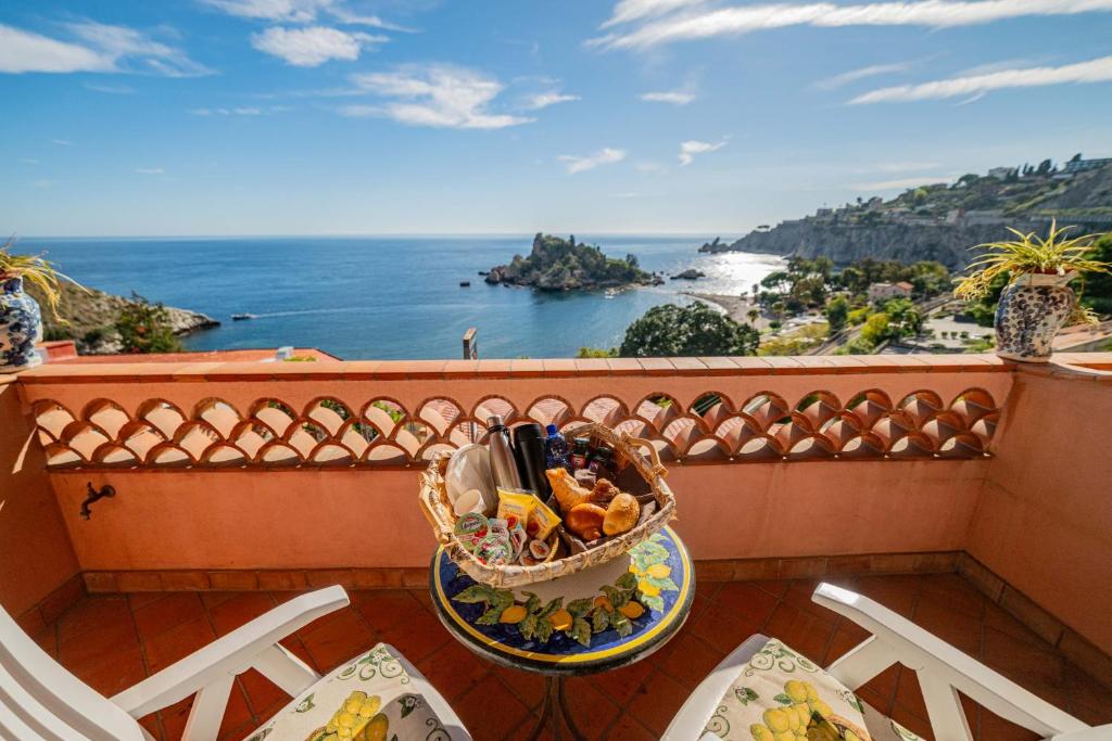 a basket of food on a balcony with a view of the ocean at Mendolia Beach Hotel in Taormina