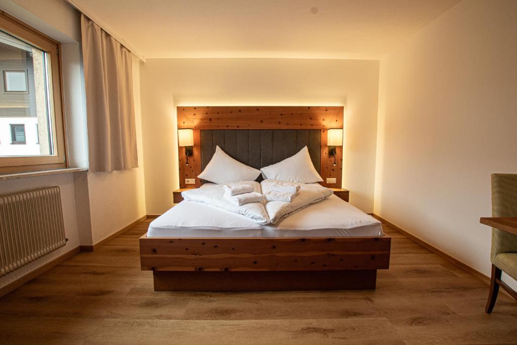 a bedroom with a bed with white sheets and pillows at Hochtenn Lodge in Zell am See - Steinbock Lodges in Zell am See