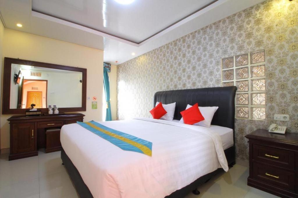 a bedroom with a large white bed with red pillows at Sultan Syariah Hotel in Bukittinggi