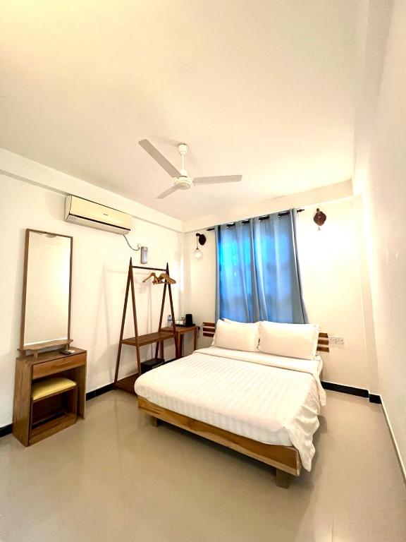 a white bedroom with a bed and a window at Leisure Boutique Maafushi 维尼家 in Maafushi