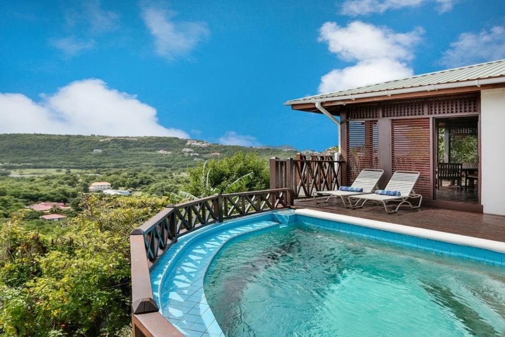 una piscina con terraza y una casa en Charming cottage located in Cap Estate - Orchid Cottage home, en Cap Estate