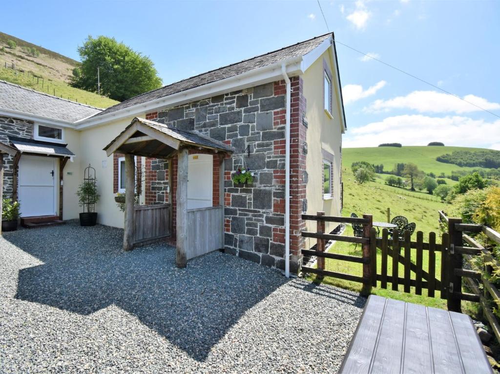 a stone cottage with a wooden gate and a fence at 2 Bed in Rhayader 45387 in Llangurig