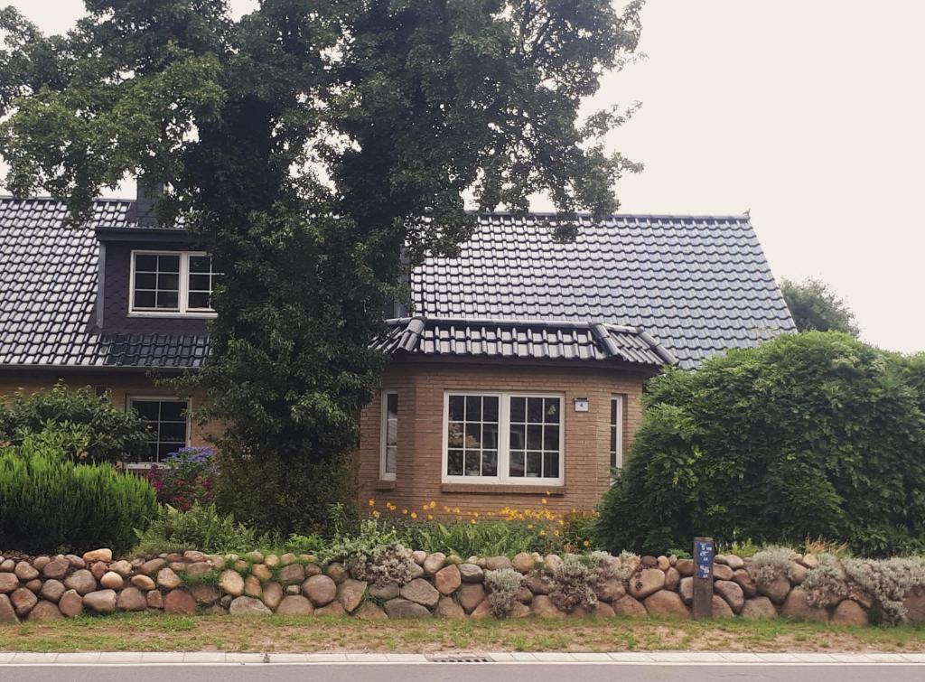 una casa con un albero e una recinzione in pietra di Ferienwohnung Hinz a Ellingstedt