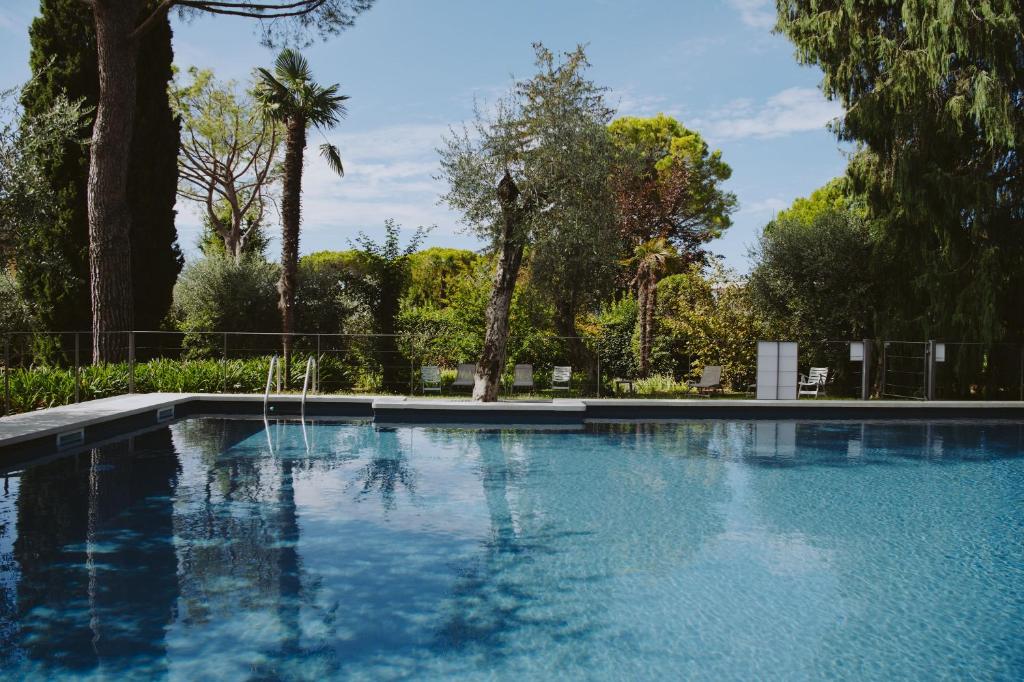 een blauw zwembad met bomen op de achtergrond bij Al segnavento Tramontana in Toscolano Maderno