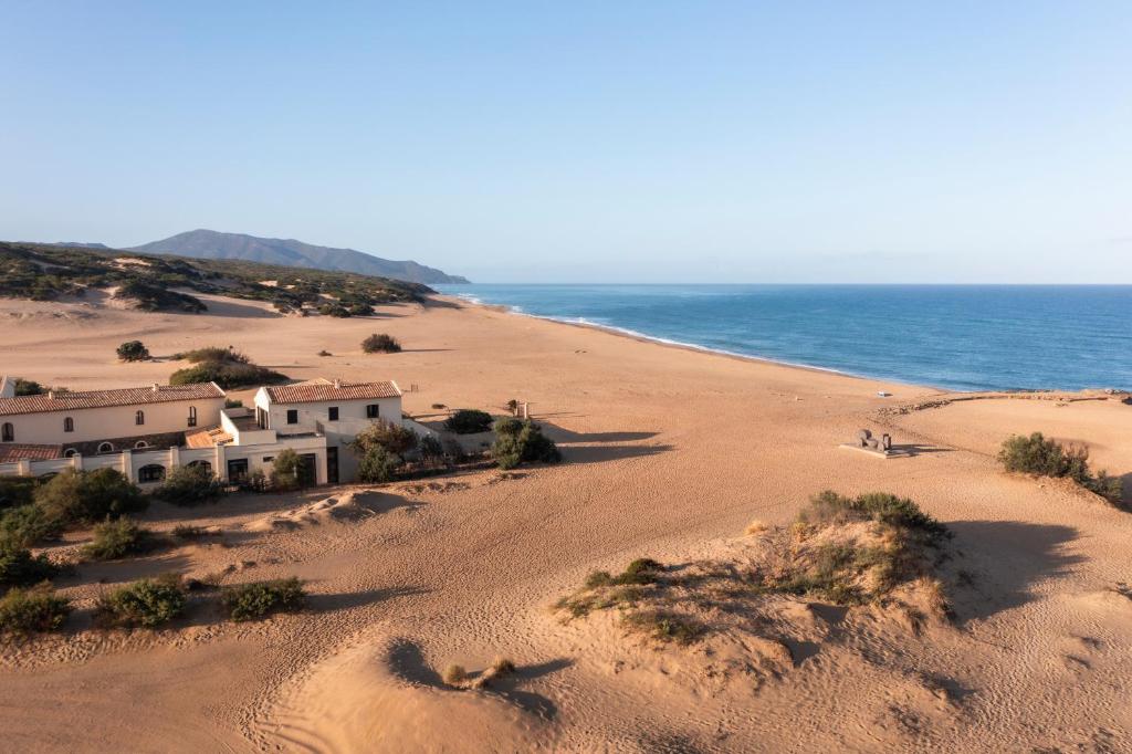 una casa en una playa de arena junto al océano en Hotel Le Dune Piscinas, en Ingurtosu