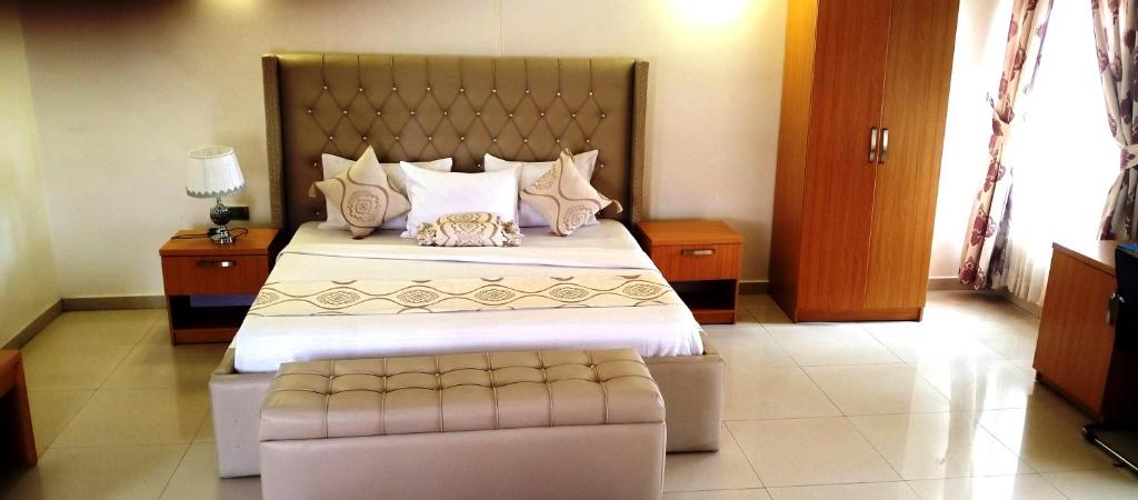 a bedroom with a large bed with a bench at the end of it at Roses Regency Hotel in Abuja