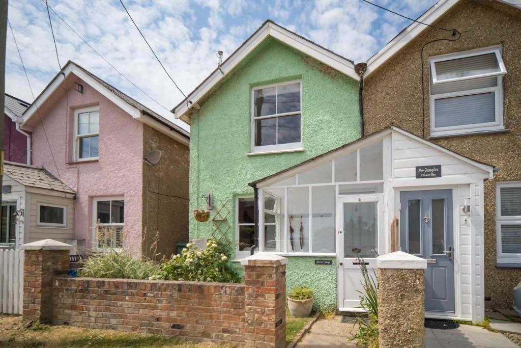 a green and pink house with a white door at Fern Cottage in Bembridge