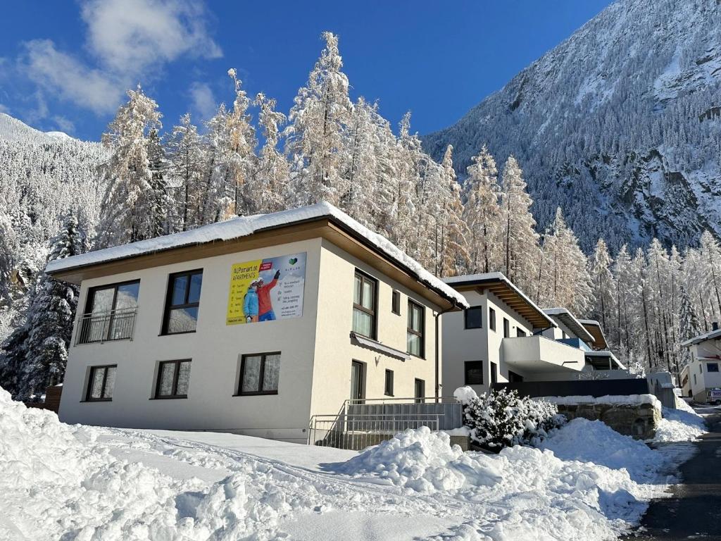 a building in the snow with snow covered trees at Apartments ALPsmart in Oetz