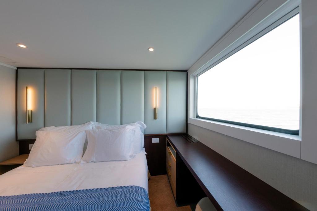 a bedroom with a bed and a large window at Costa do Sal Hotel Boat Lounge in Aveiro
