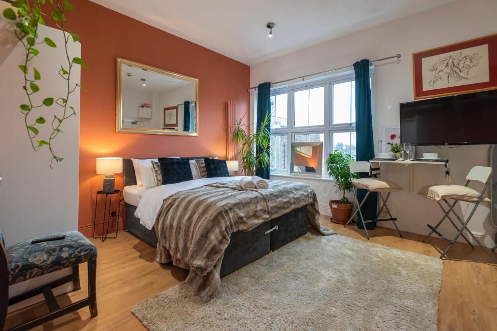 Amazing Finsbury Park Studio في لندن: غرفة نوم بجدران برتقالية وسرير وتلفزيون