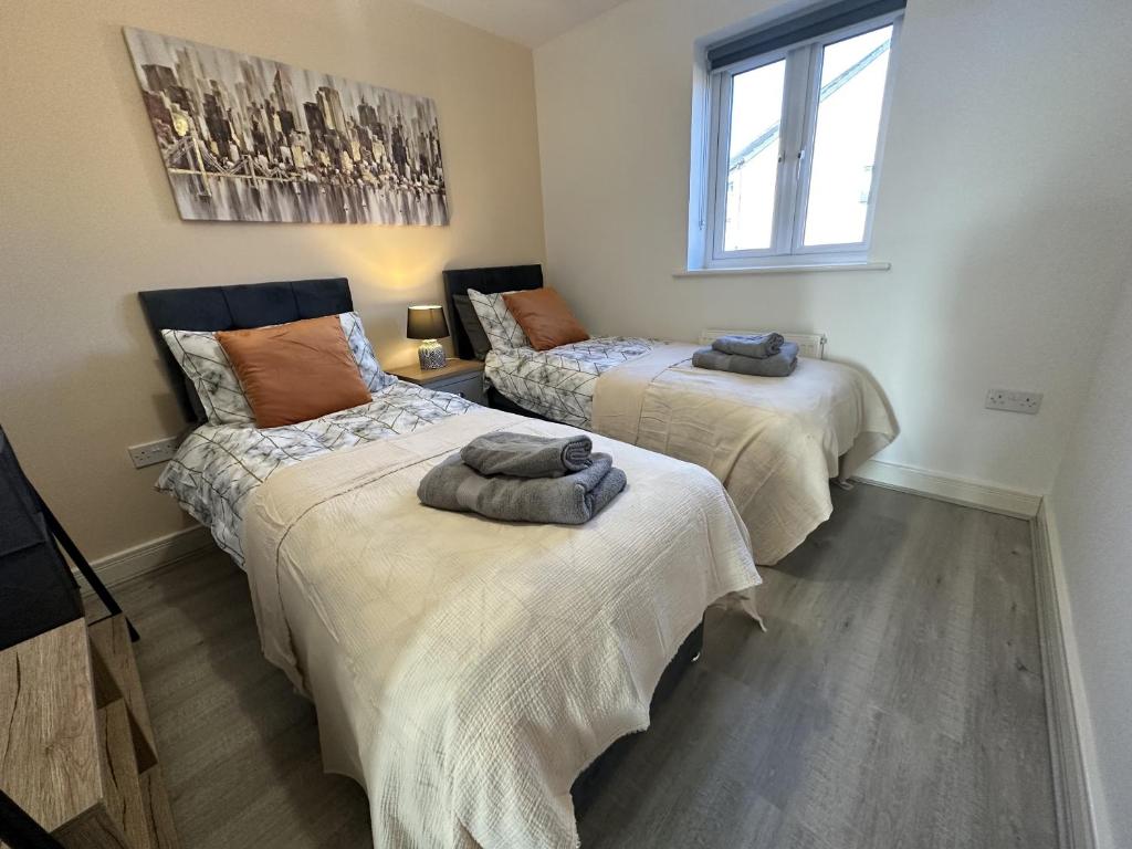 a room with two beds with towels on them at 3 Bed Home for Contractors Relocators with Parking Garden WiFi Sleeps 6 in Milton Keynes