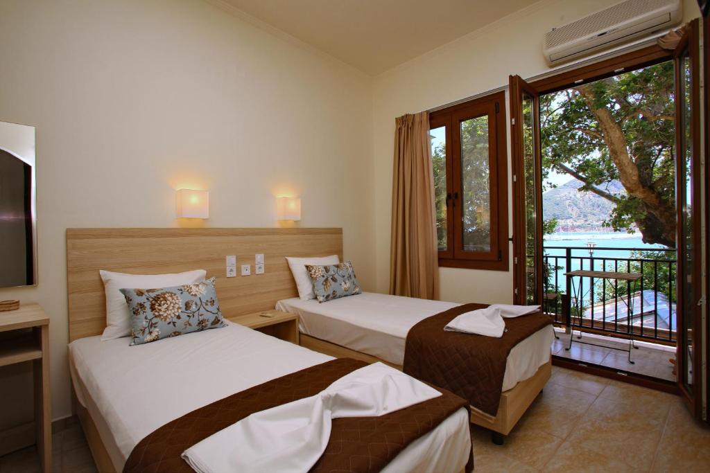 a hotel room with two beds and a balcony at Aktaion Guest Rooms in Skopelos Town