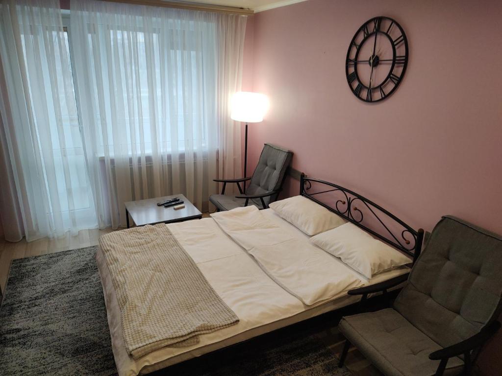 1 dormitorio con 1 cama y reloj en la pared en Апартаменти, вул Космонавтів,29, великий Смарт TV , преміум підписки, en Krivoy Rog