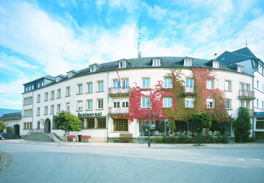 ein großes weißes Gebäude mit Blumen auf der Seite in der Unterkunft Hotel Kinnen in Berdorf