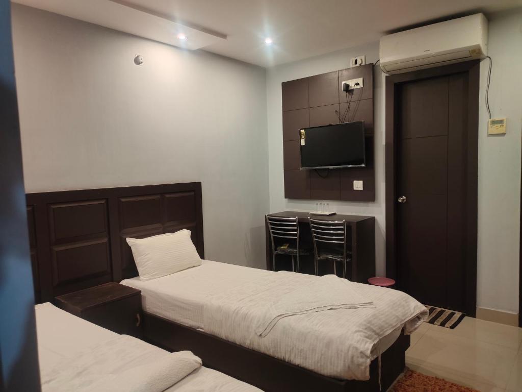 una camera d'albergo con due letti e una televisione di HOTEL IMF a Patna