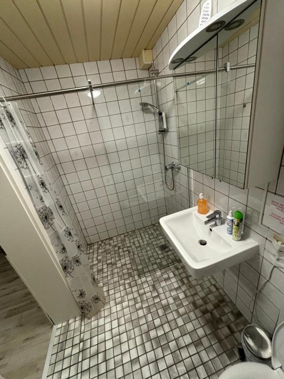 La salle de bains est pourvue de carrelage blanc, d'un lavabo et d'une douche. dans l'établissement Quartier Wenzelnberg work&stay, à Langenfeld