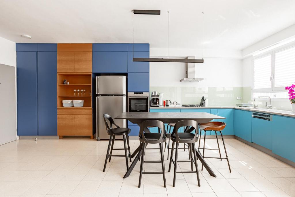 cocina con armarios azules, mesa y sillas en Appartements BnBIsrael - Hovevei Tsiyon Jasmin, en Tel Aviv
