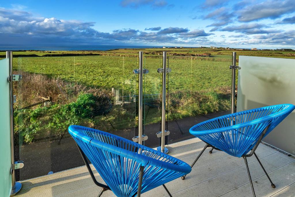 two blue chairs on a balcony with a view of a field at Finest Retreats - Treknow Summerhut in Tintagel