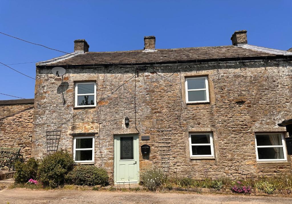 an old stone house with a green door at Brookside in Langthwaite